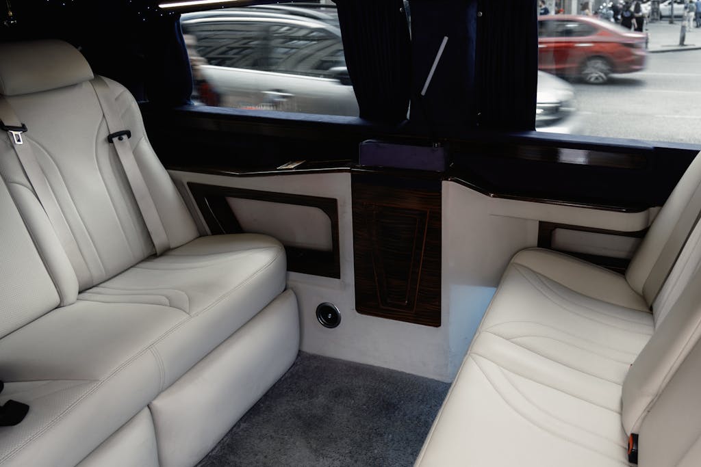 Interior view of a luxury limousine showcasing white leather seating with stylish design and amenities.